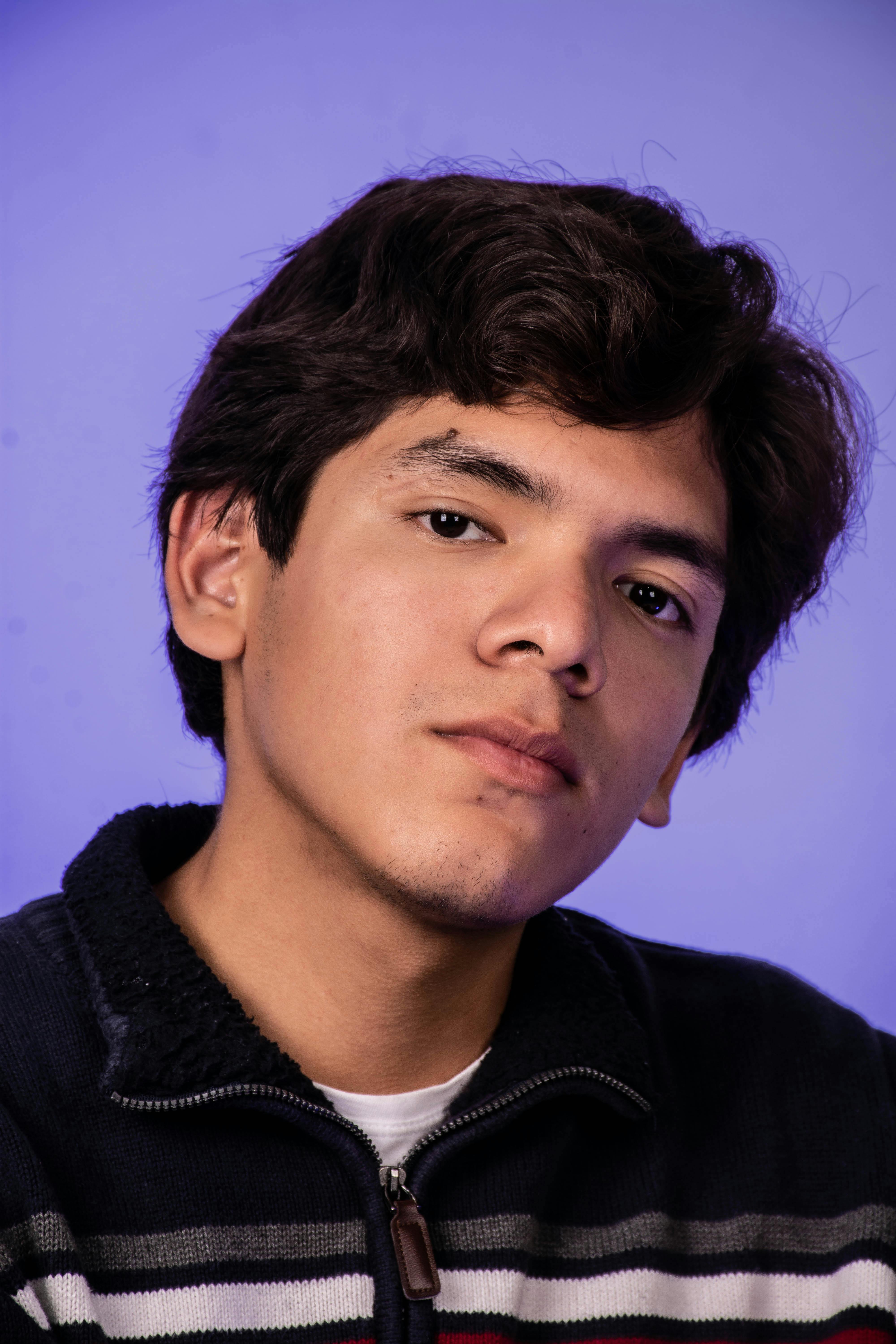 Close-up portrait of a young man against a blue backdrop.