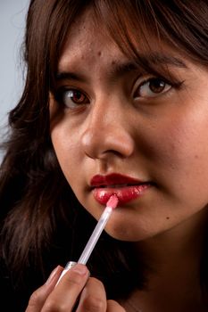 Close-up portrait of a woman applying lip gloss, highlighting beauty and makeup.