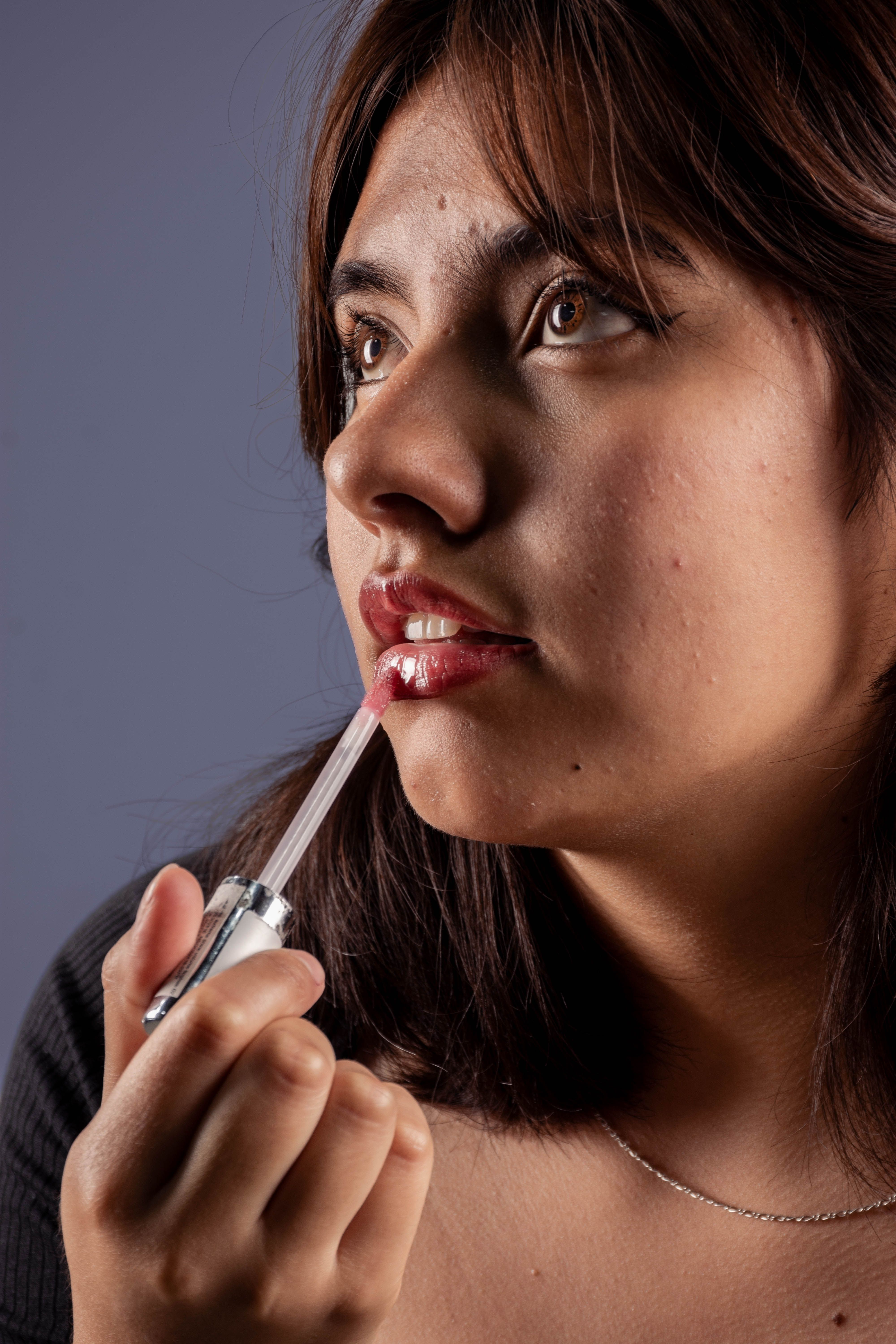 Close-up portrait of woman applying lip gloss
