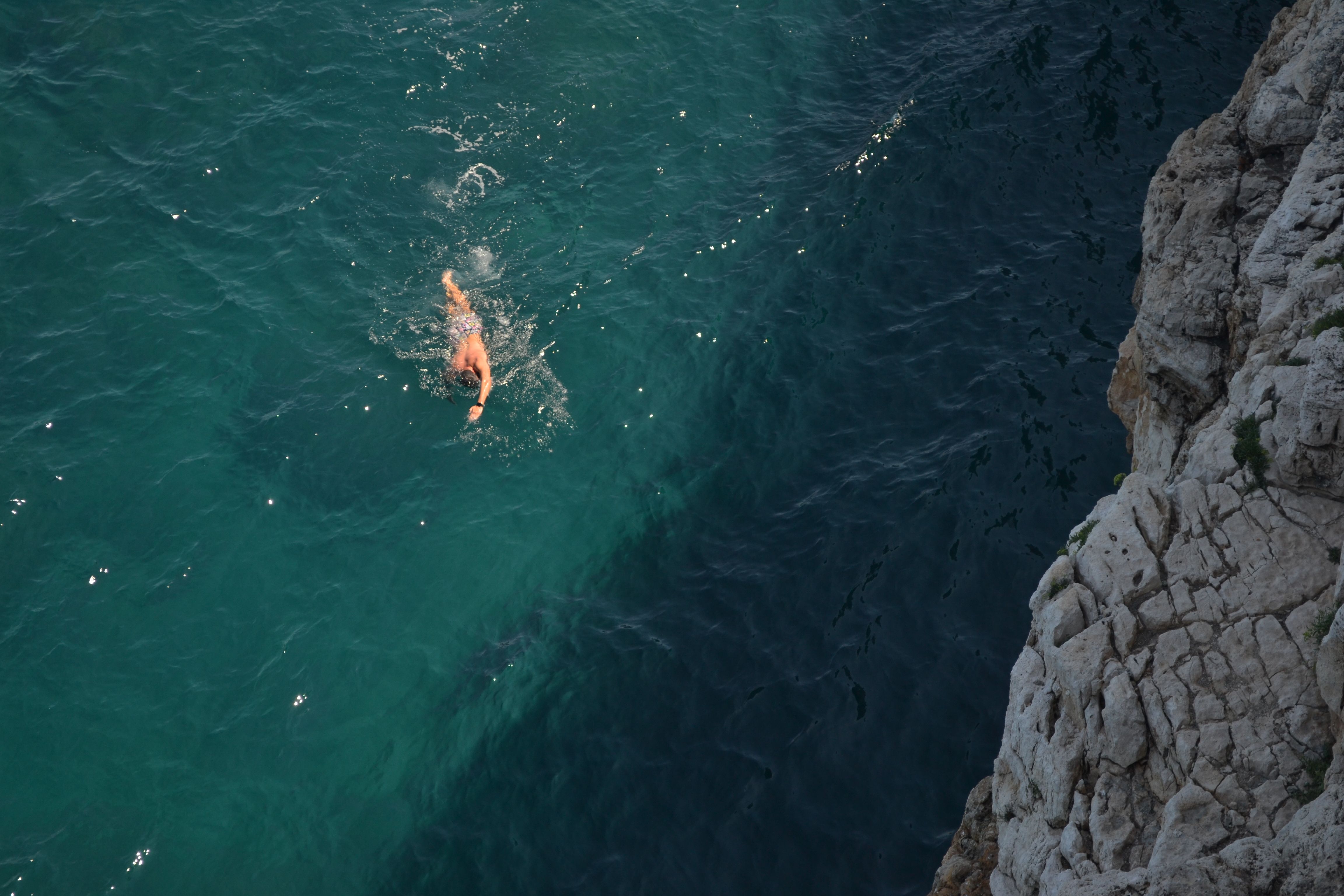 A swimmer in the blue sea by rocky cliffs at Polignano a Mare, Italy. - Photo by Ciro Palomba on Pexels