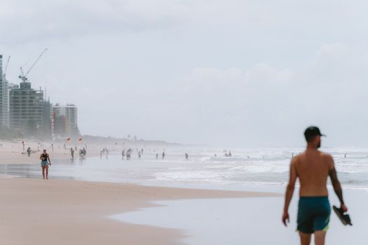 Beachgoers enjoy the sandy shores of Surfer's Paradise, Queensland, under cloudy skies.