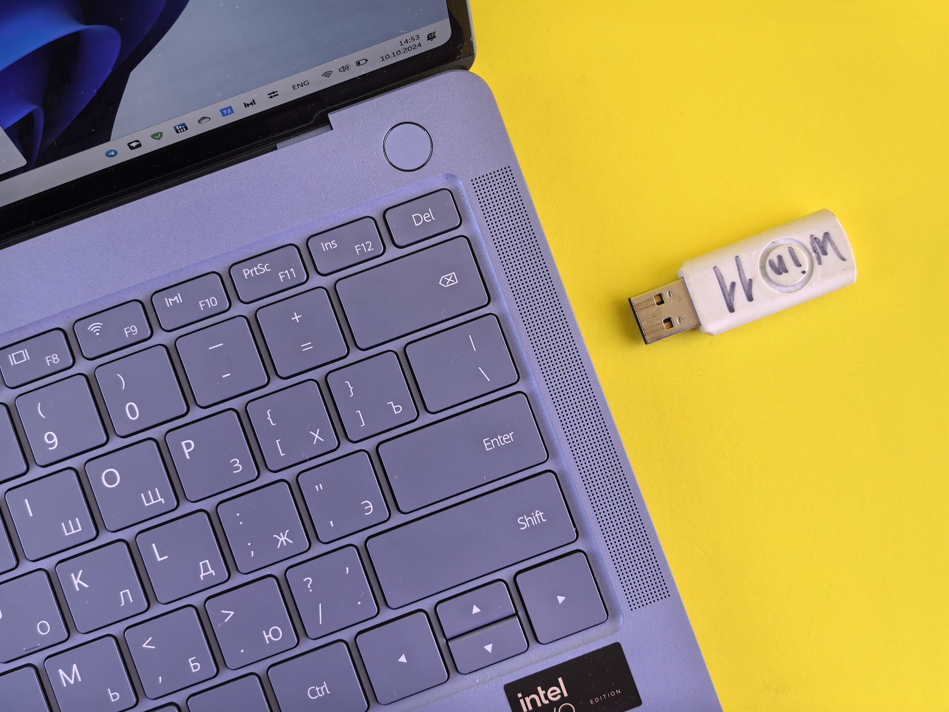 Close-up of a purple laptop keyboard with a USB on a yellow background, showcasing tech accessories.