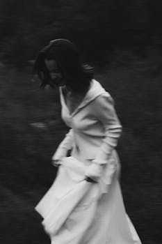 A captivating black and white image of a woman in motion in a mysterious setting.