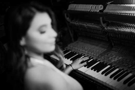 A blurred artistic shot of a woman playing a piano in black and white.
