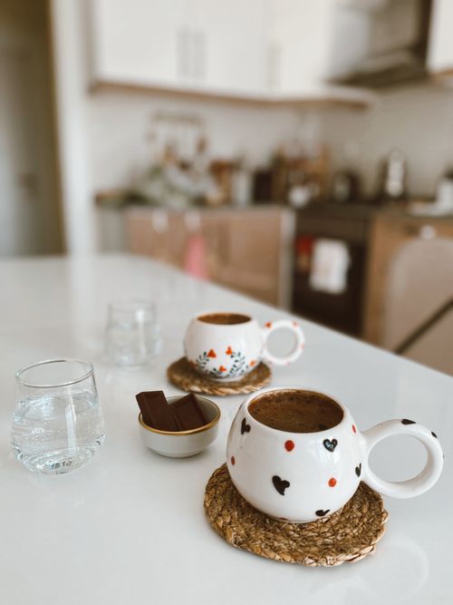 Free Two decorated mugs with coffee on a kitchen countertop, creating a cozy atmosphere. Stock Photo