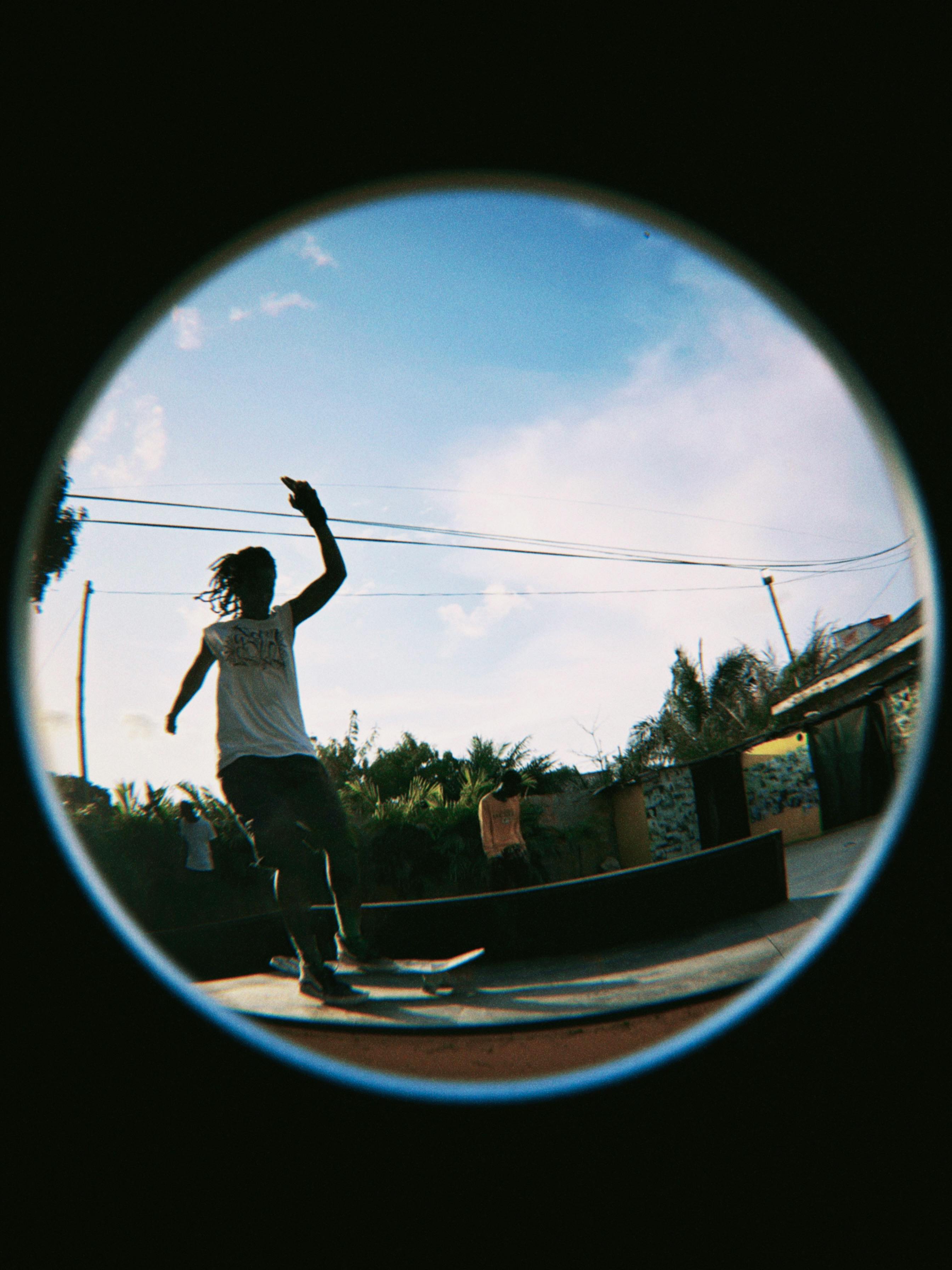 A skateboarder skillfully glides in a fish-eye view, showcasing an urban park
