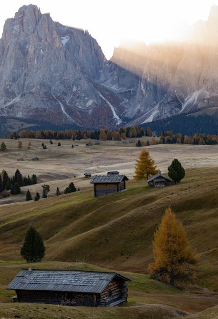 Beautiful landscape of wooden cabins in the Dolomites with sunset lighting and autumn colors.