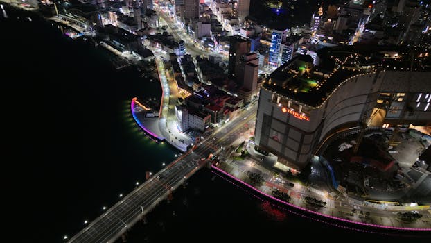 Stunning aerial night view of Busan with illuminated streets and buildings.