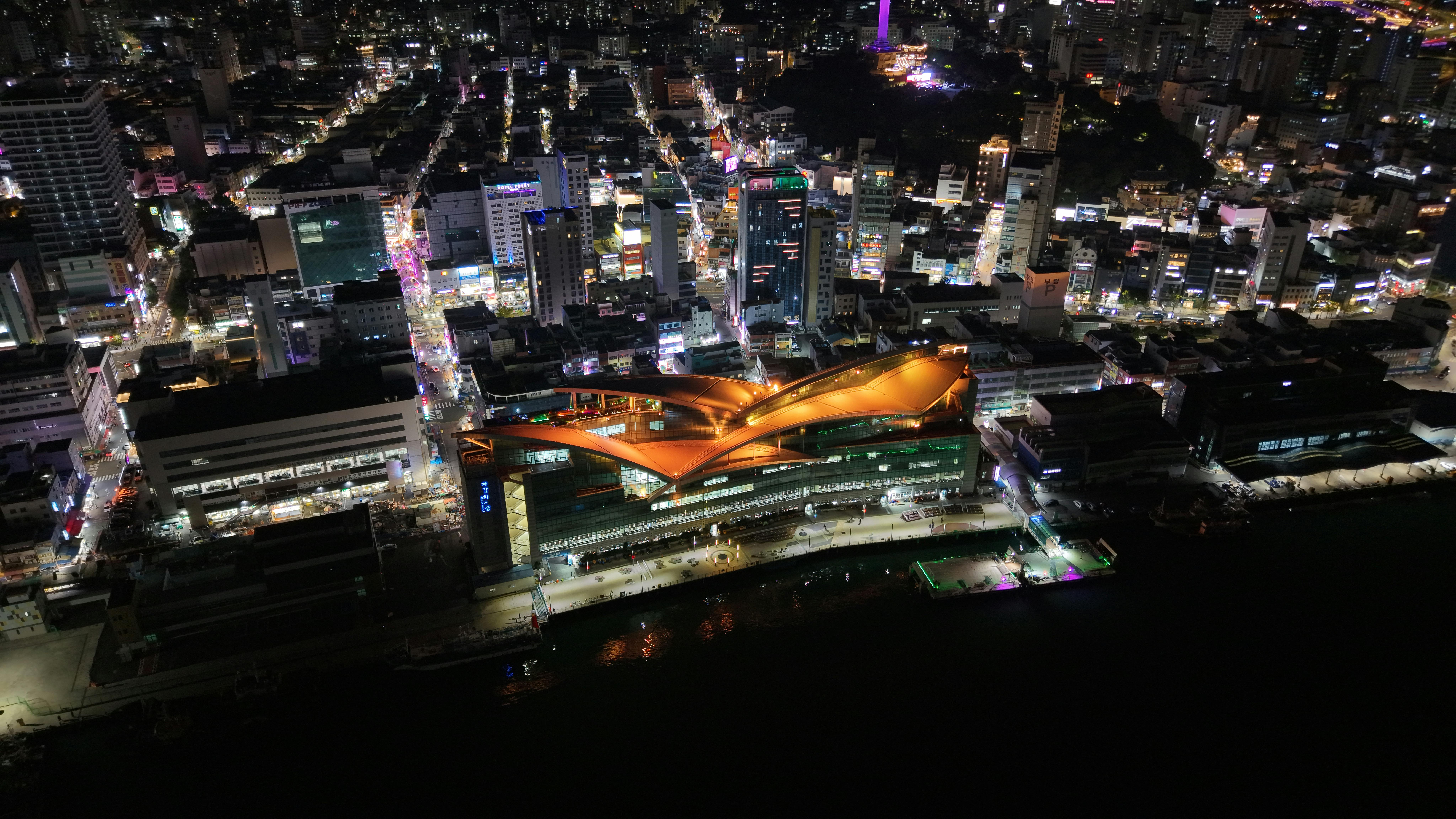 Vibrant night aerial view of Busan city illuminated with urban lights and modern architecture.