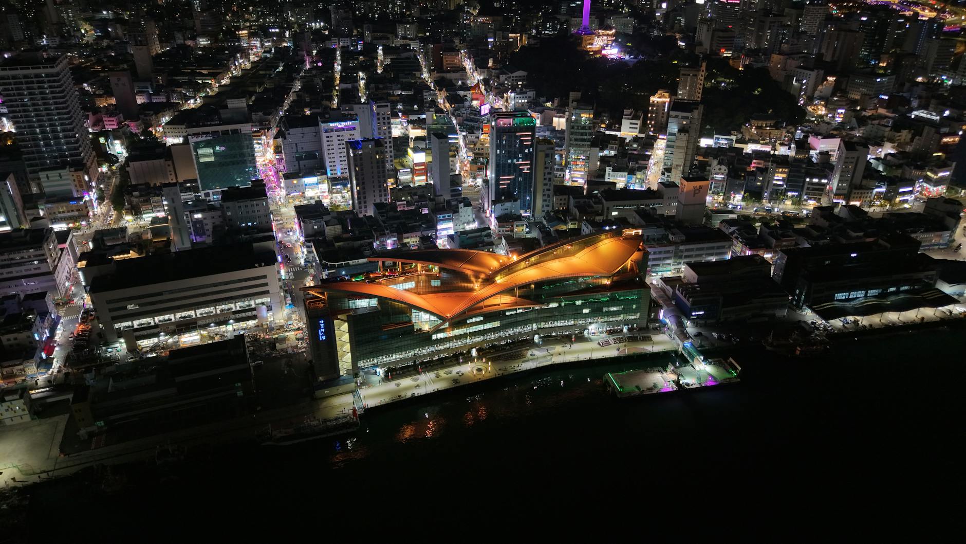 Vibrant night aerial view of Busan city illuminated with urban lights and modern architecture.