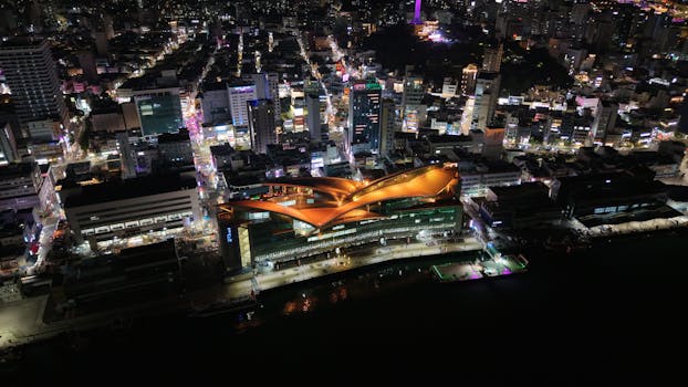 Vibrant night aerial view of Busan city illuminated with urban lights and modern architecture.