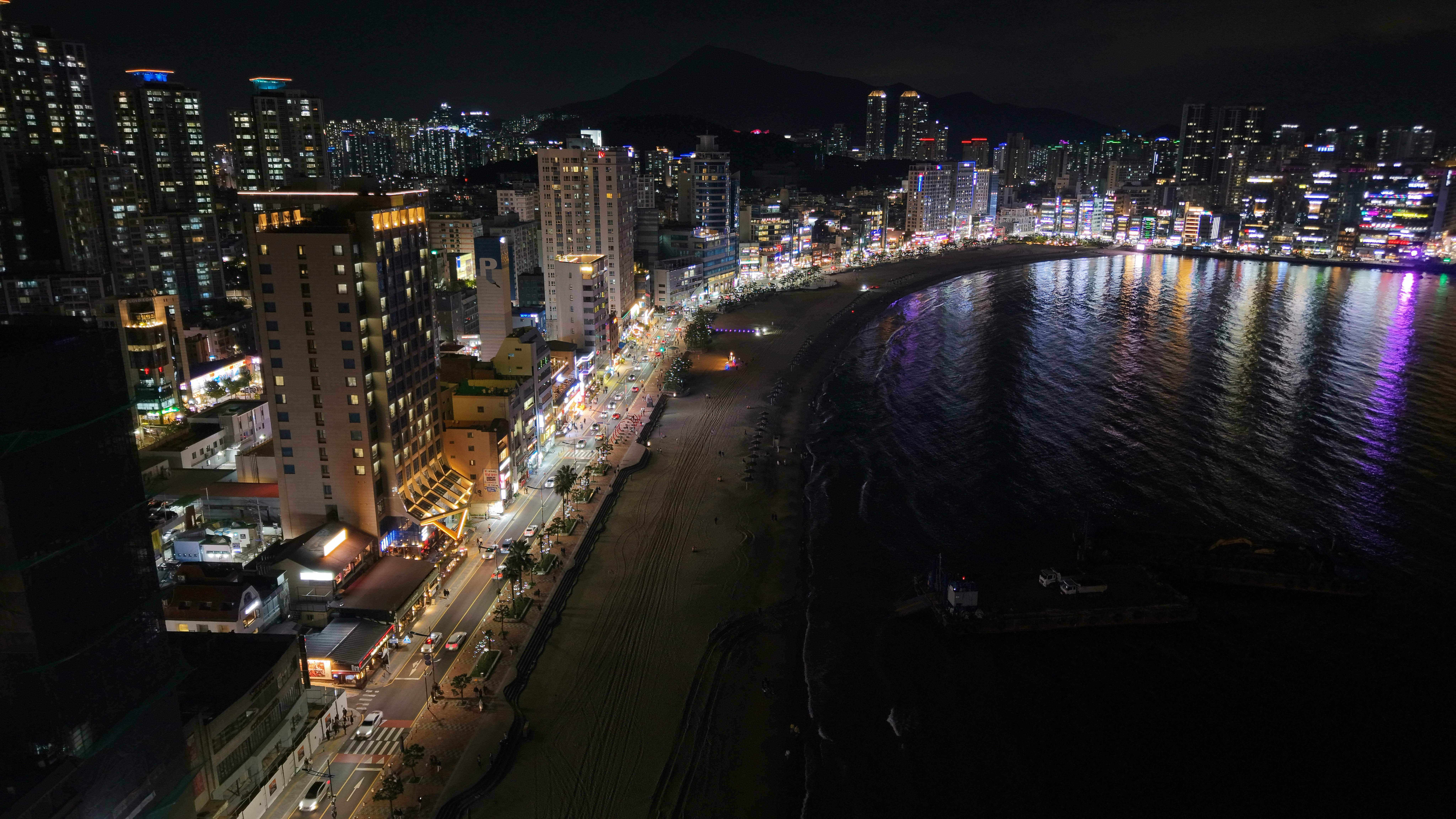 Stunning night view of Busan's skyline and beach, showcasing vibrant city lights.