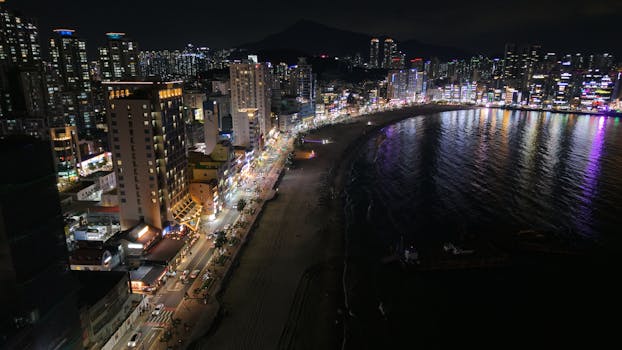 Stunning night view of Busan's skyline and beach, showcasing vibrant city lights.