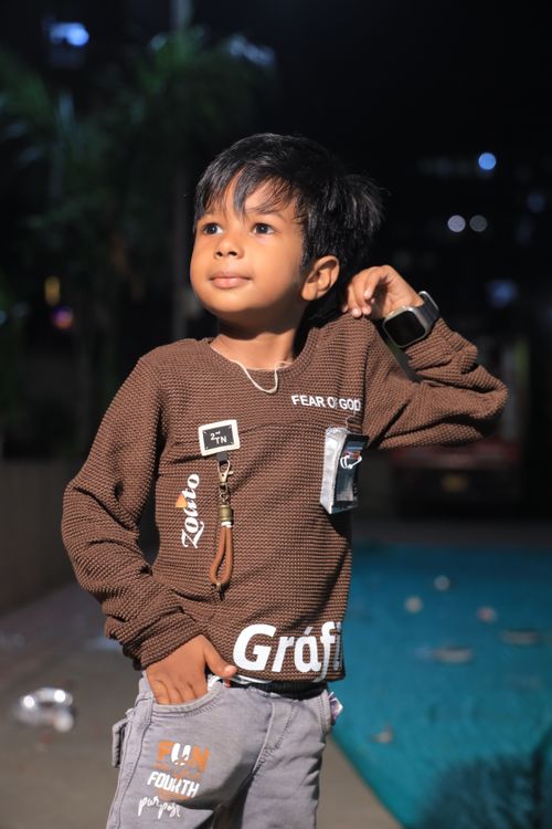 Free Portrait of a confident child posing outdoors at night with city lights in the background. Stock Photo