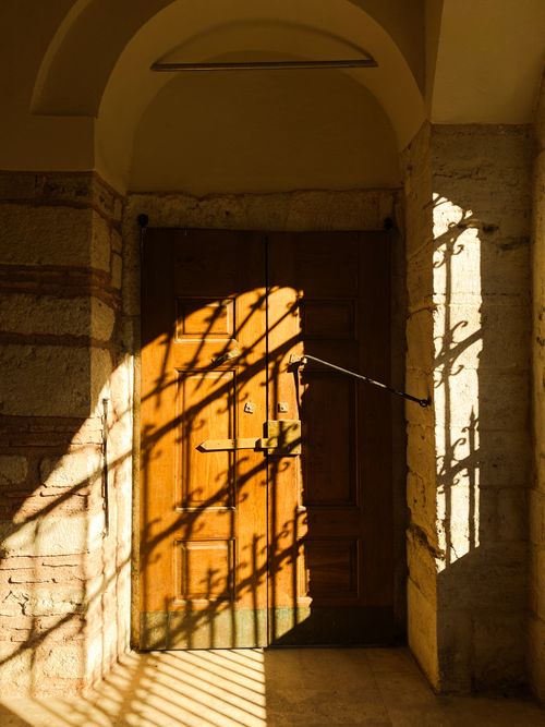 Free Sunlight casts intricate shadows on a wooden door, creating a warm, inviting scene. Stock Photo