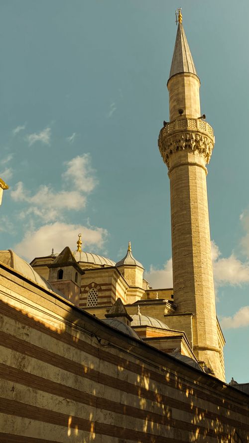 Free A tall, elegant minaret of a historic mosque stands under a bright blue sky. Stock Photo