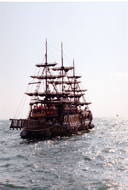 Majestic pirate ship with sails unfurled journeying across a sunlit ocean.
