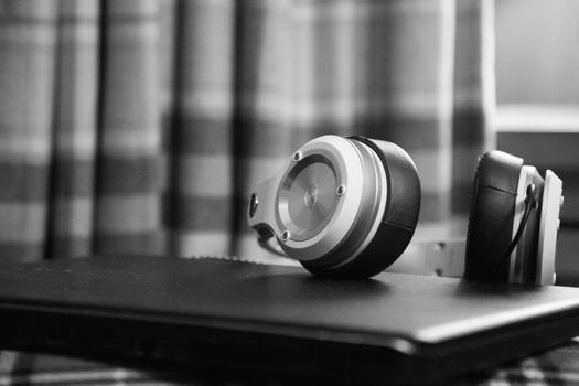 Black and white headphones placed on laptop, indoors. Elegantly composed with soft focus.