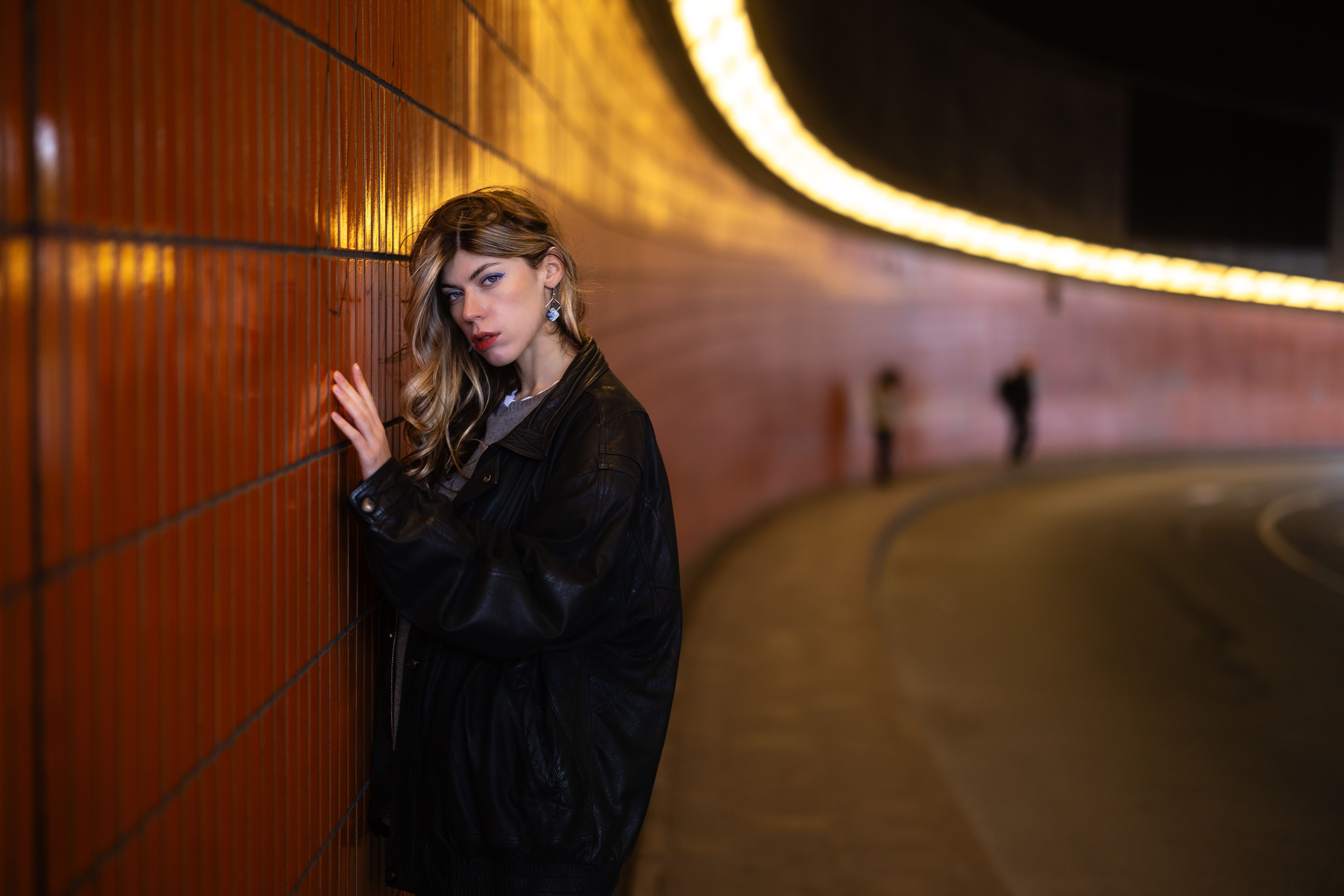 Femme en veste de cuir dans un passage urbain éclairé