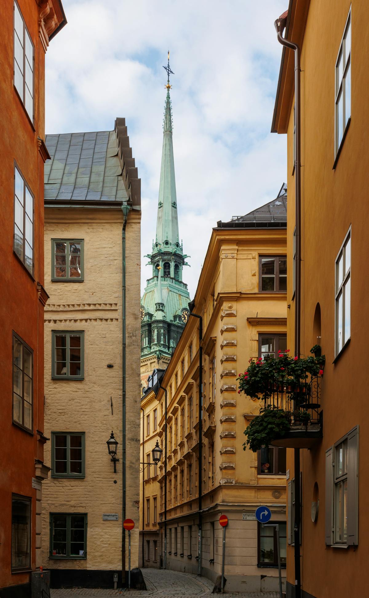 A narrow cobblestone street in Gamla Stan, Stockholm — medieval architecture and church spires in the early morning