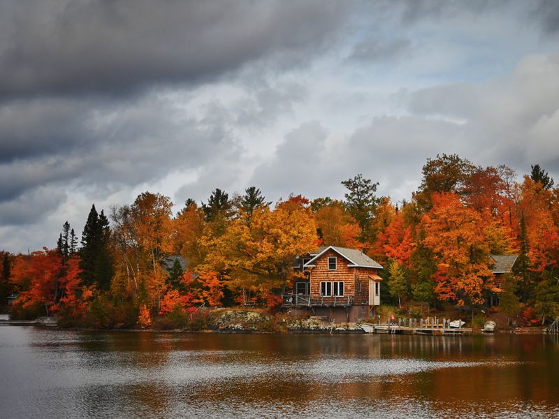 Lakeside cabin surrounded by autumn foliage — photo by William Liu on Pexels
