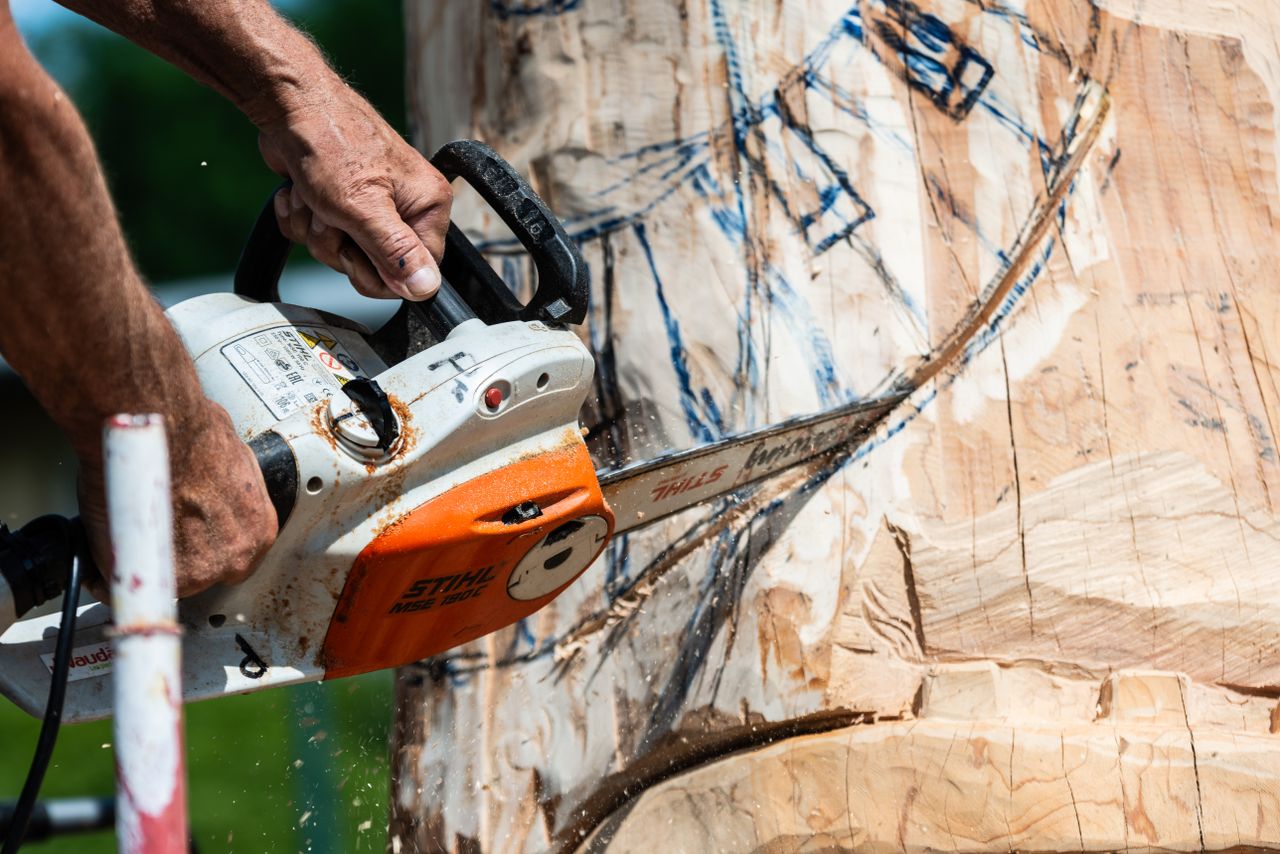 close up of an artist using a chainsaw for intricate wood carving outd