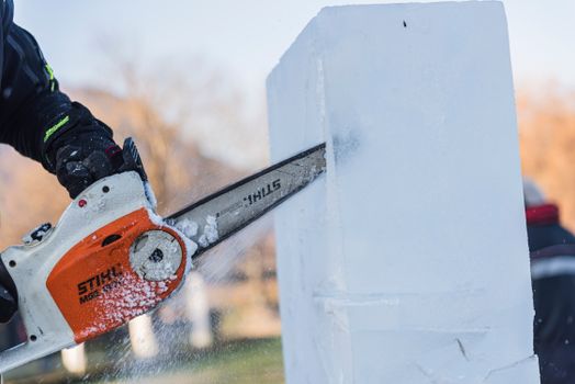 Close-up of a chainsaw carving an ice block into a sculpture during winter.
