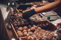 Hand picking delicious chocolates in a shop display with variety.