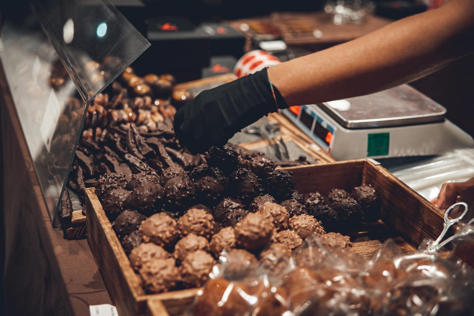 Hand picking delicious chocolates in a shop display with variety.