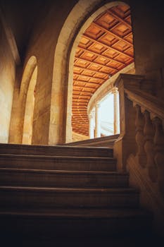 Elegant stone architecture featuring arches and a staircase in a historic Spanish building.