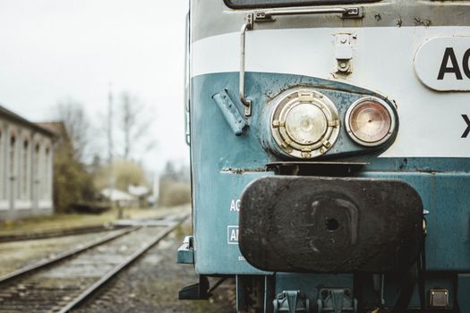 Vintage blue train locomotive at an empty station on a cloudy day.