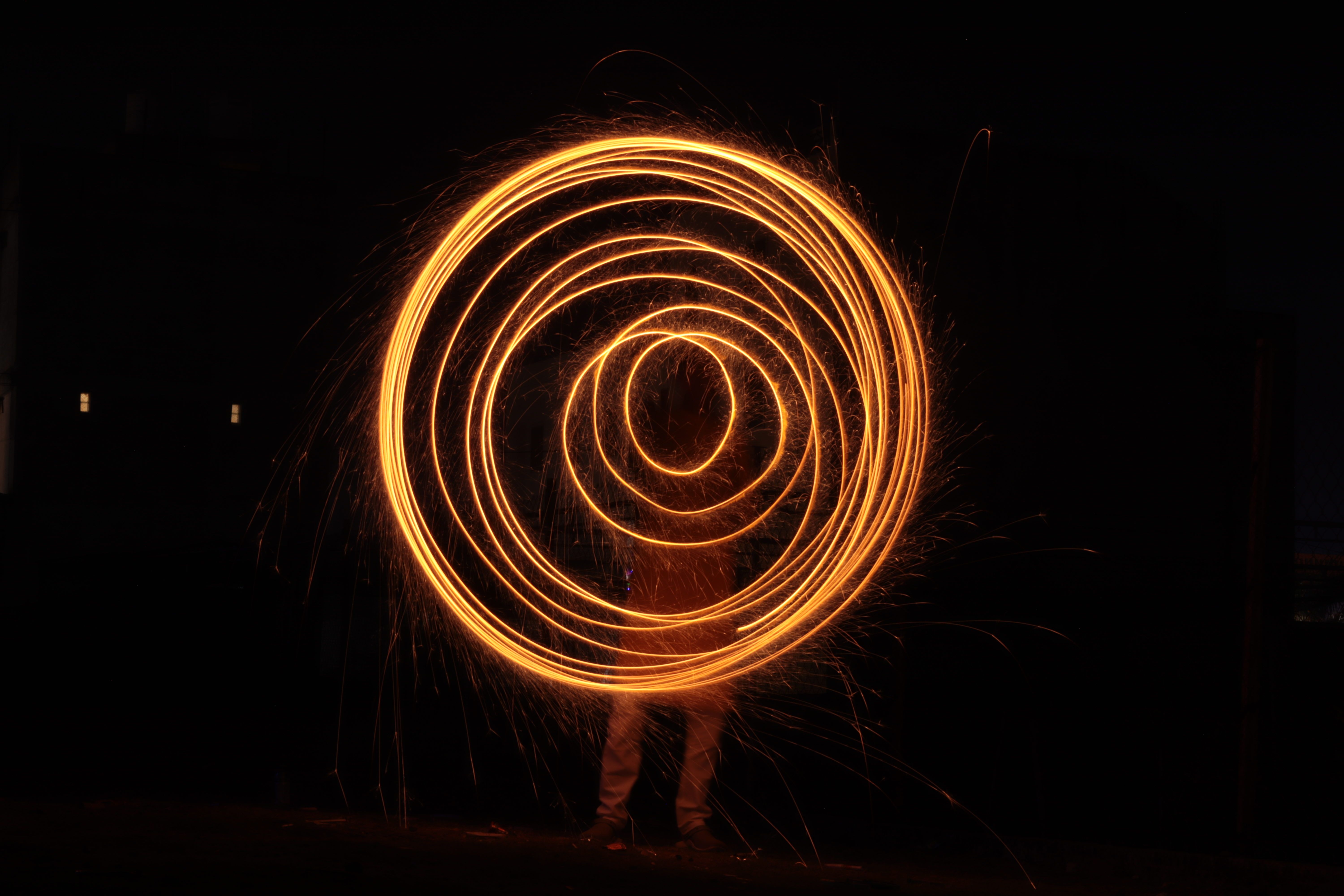 Captivating long-exposure light painting creating fiery spiral patterns against a dark night backdrop.