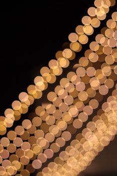 Warm yellow bokeh of string lights creating an abstract pattern on a dark background.