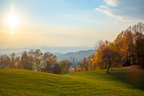 Free Beautiful fall landscape with colorful trees and soft sunlight over rolling hills. Stock Photo