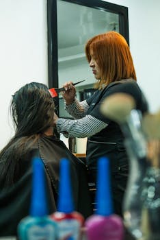 A stylist applies hair color to a client in a modern salon setting.