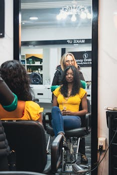 A woman getting a hair treatment in a salon, looking in the mirror.