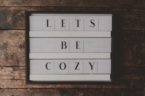 Free A cozy sign with wooden texture saying 'LETS BE COZY' for interior design inspiration. Stock Photo