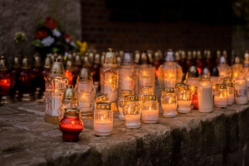 Free A serene scene of votive candles glowing softly in a cemetery during All Saints' Day. Stock Photo