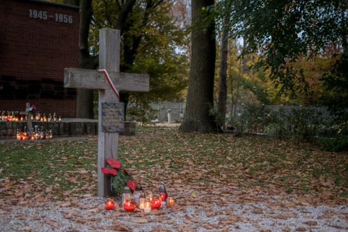 Free A peaceful cemetery scene with a cross, memorial candles, and autumn leaves. Stock Photo