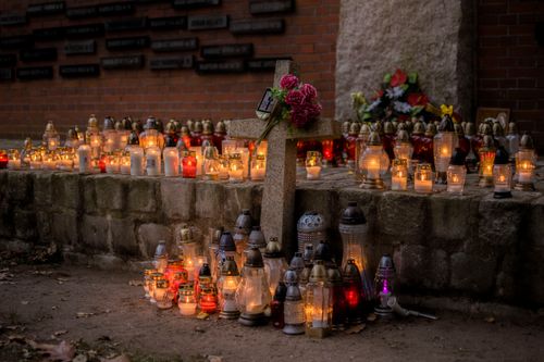 Free Lit candles and cross at cemetery, symbolizing All Saints' Day remembrance. Stock Photo