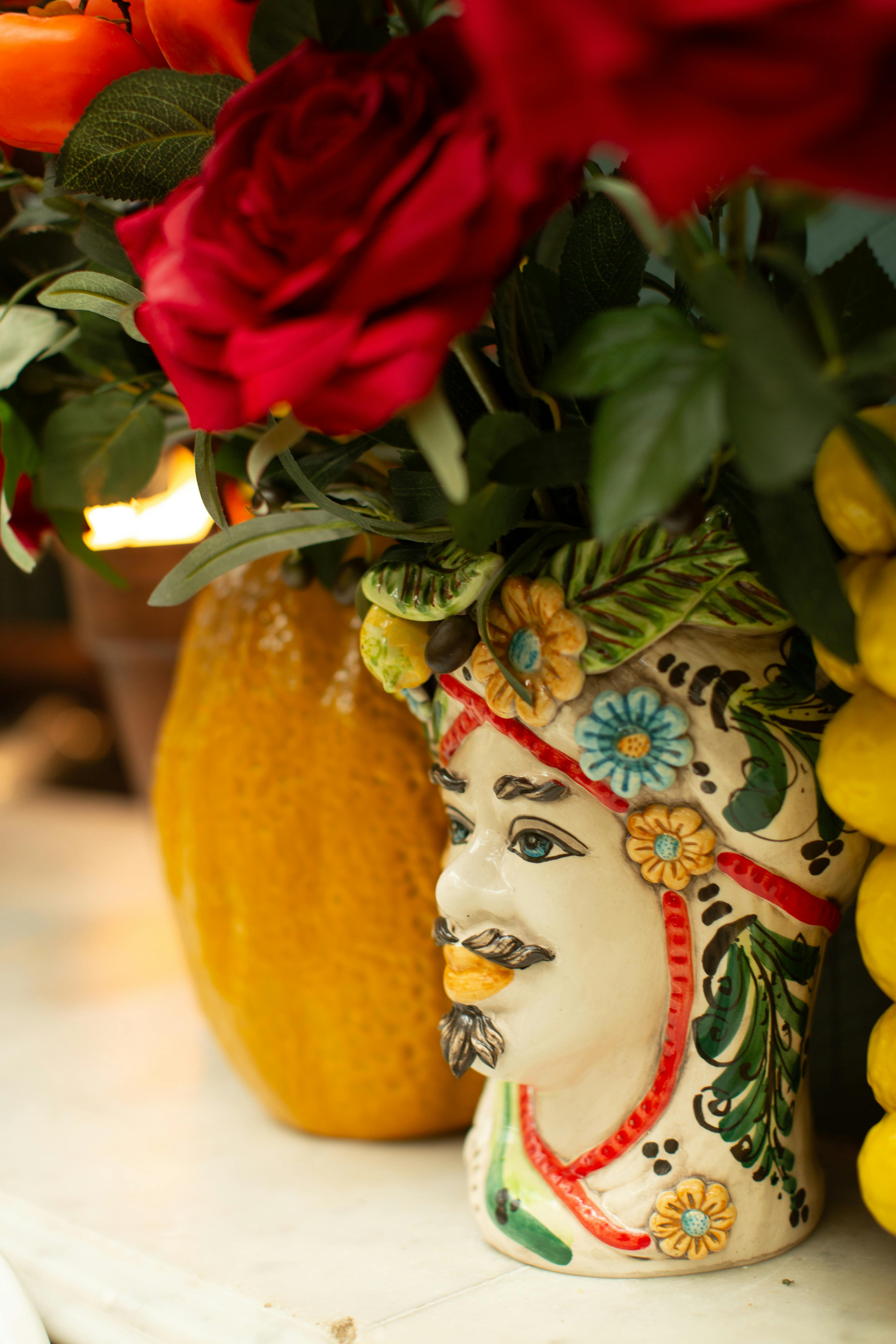 Close-up of colorful flowers in an ornate face-themed vase.