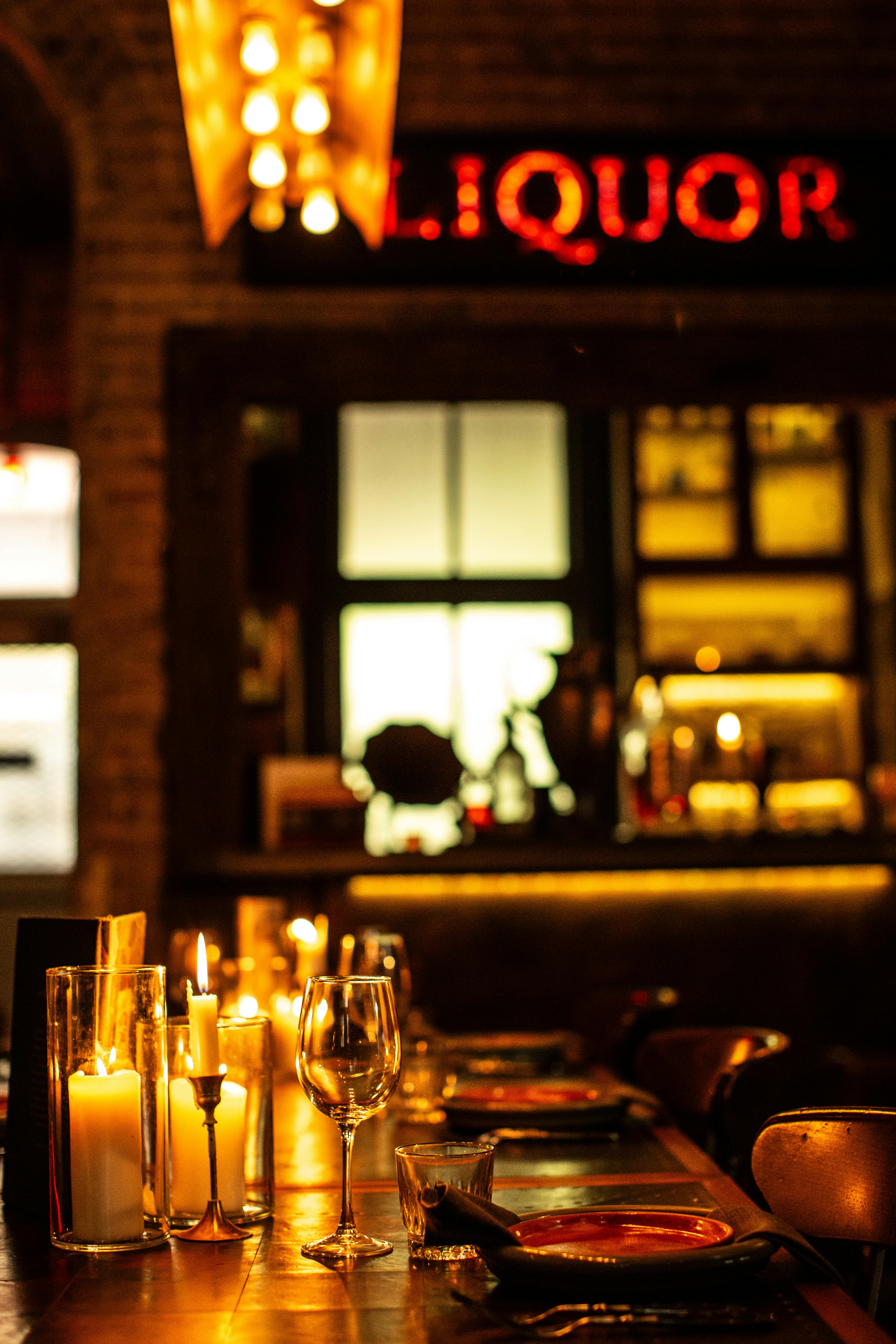 Warm candlelit dinner setting with wine glasses in a cozy Alexandria bar.