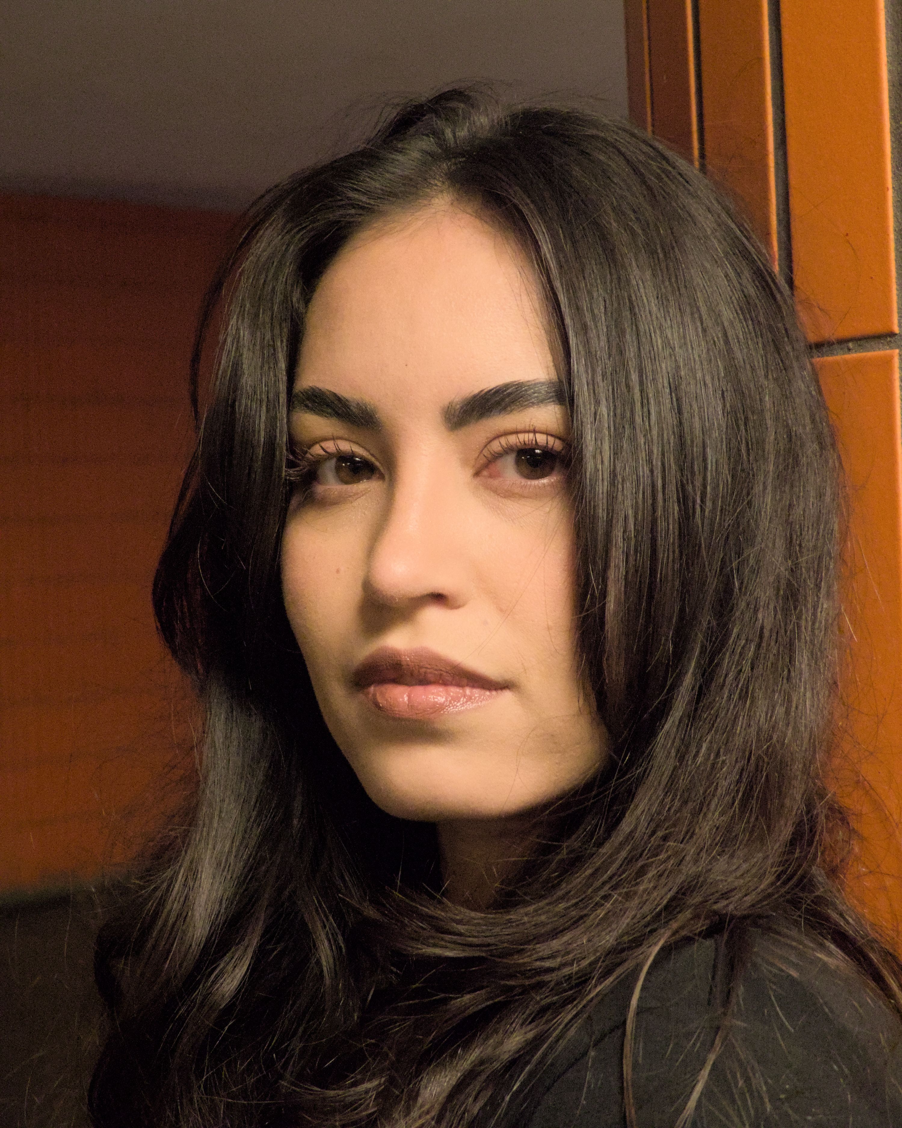 Close-up portrait of a woman with long hair against a wooden backdrop in Berlin.