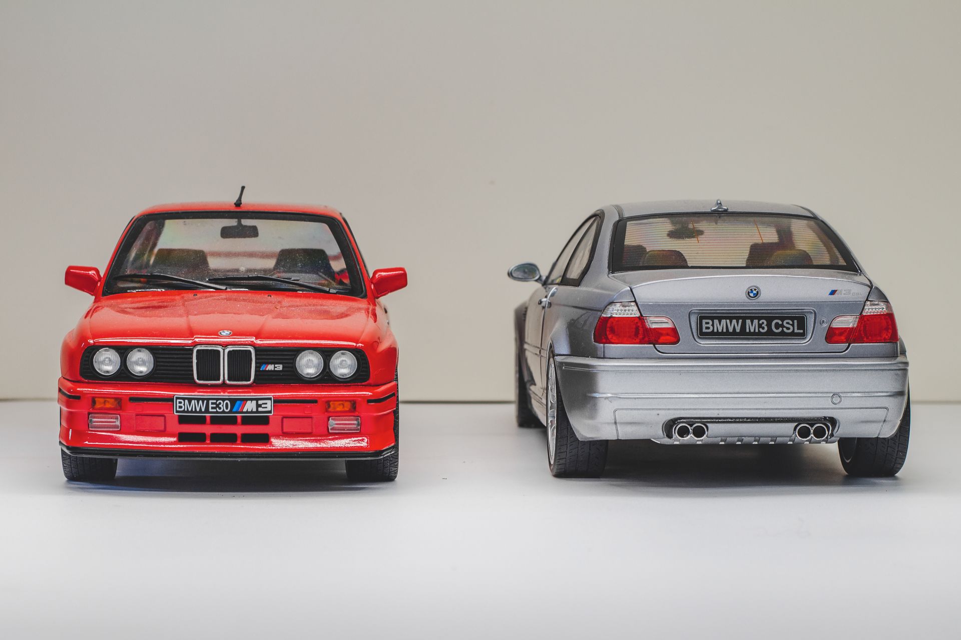 Front view of red BMW E30 M3 and rear view of silver BMW E46 M3 CSL models.