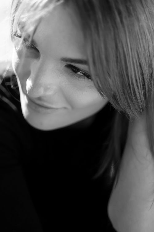 Free Captivating black and white portrait of a smiling woman looking downwards with soft lighting. Stock Photo