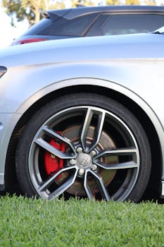 Detailed view of a luxury car wheel with red brake calipers on grass.