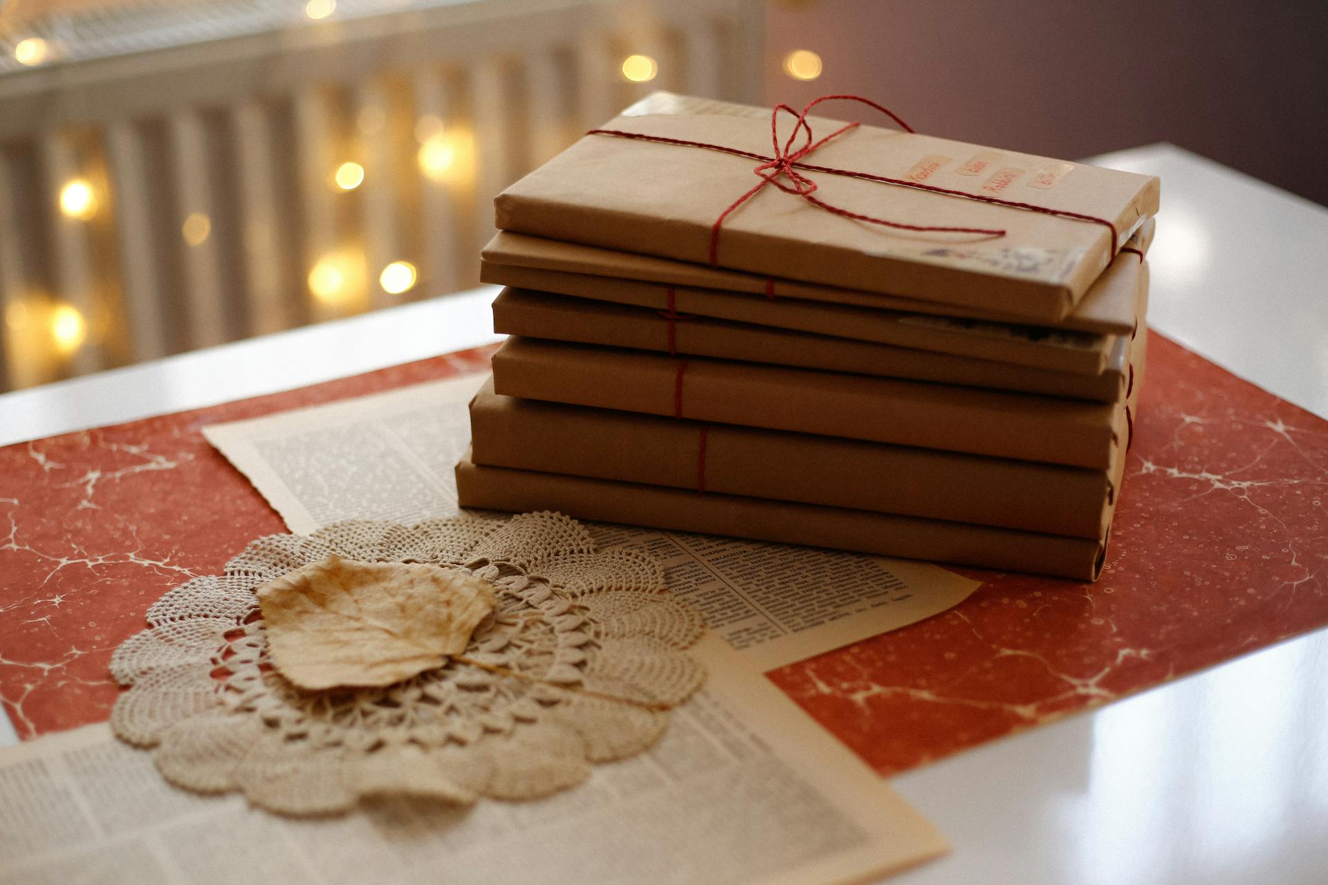 Stack of vintage books wrapped in brown paper and tied with string on a decorative table setting.