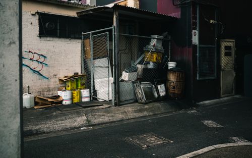 Free A gritty urban alleyway featuring industrial waste, graffiti, and dim lighting. Stock Photo