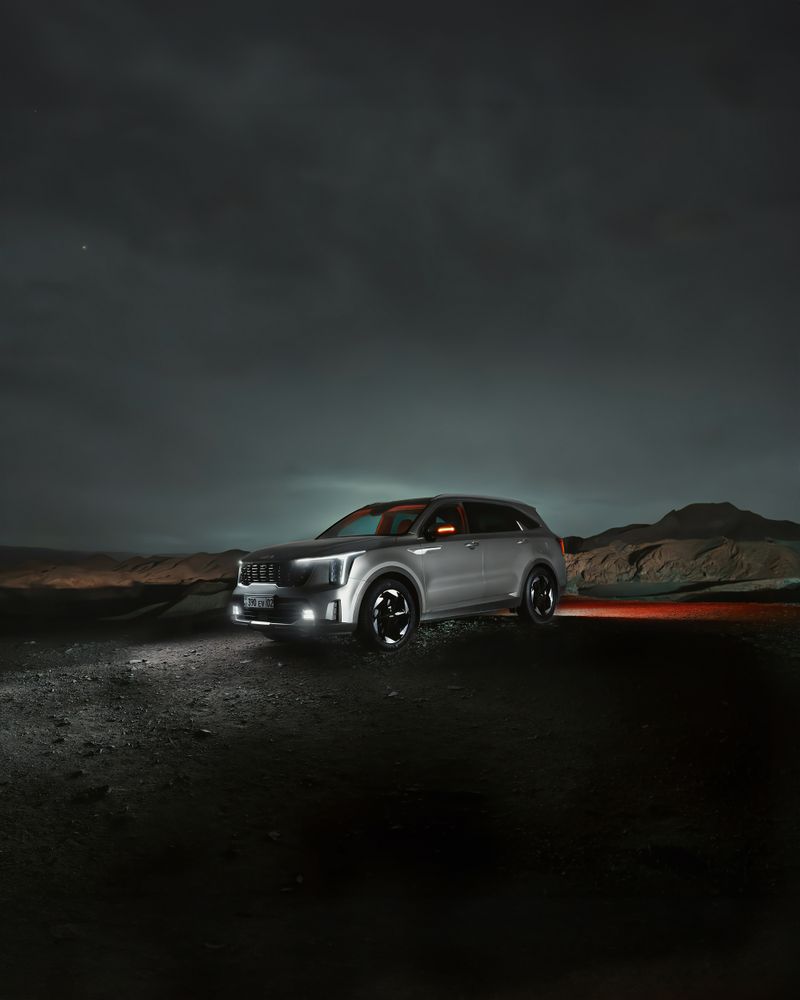 A stylish SUV parked in open terrain under a dramatic night sky