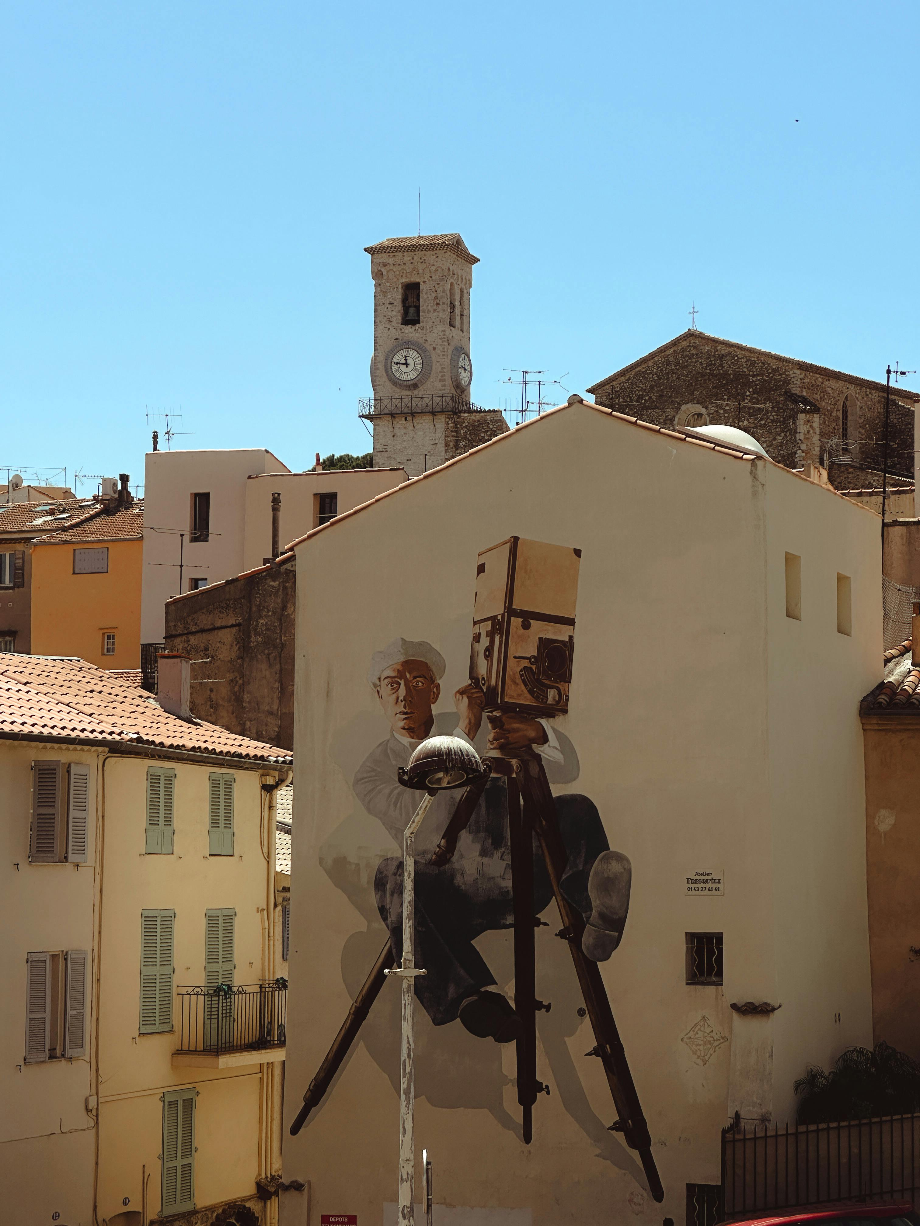 A striking mural in Cannes, featuring a street art camera against a backdrop of historic architecture.